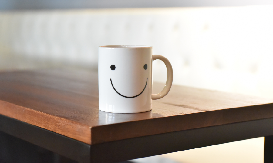 A coffee cup with a smile face on it