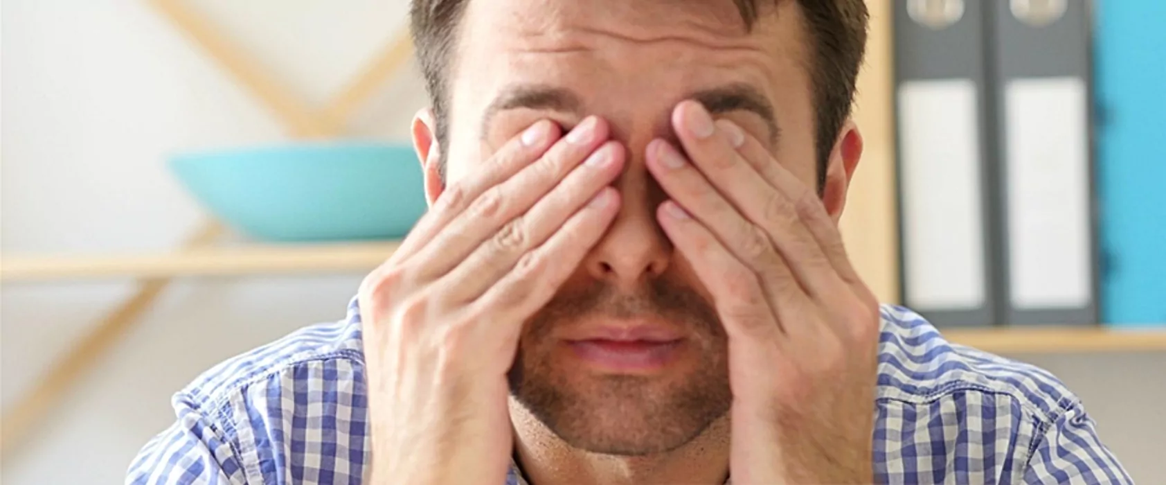 A man visibly uncomfortable, covering his eyes