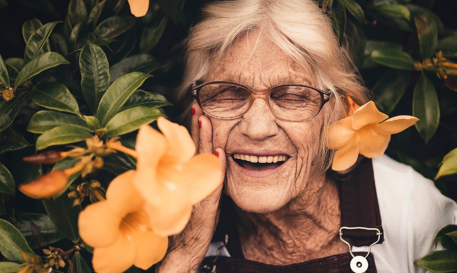 Eldery woman smiling, next to a flower bouquet