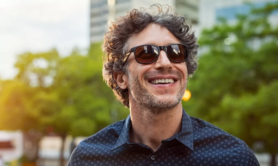 A man in a park with sunglasses, smiling