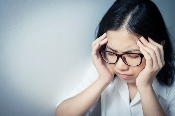 A woman with glasses with a headache