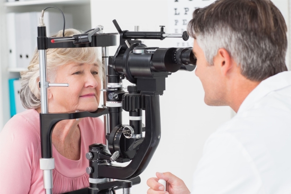 A photo of a doctor performing eye exam on an elderly woman