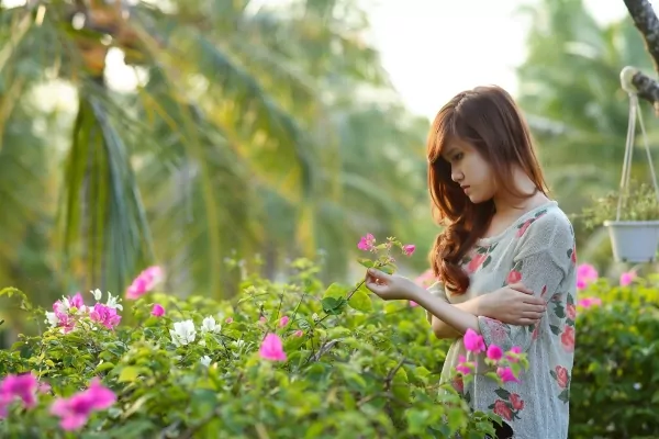 A womain in a park picking up flowers